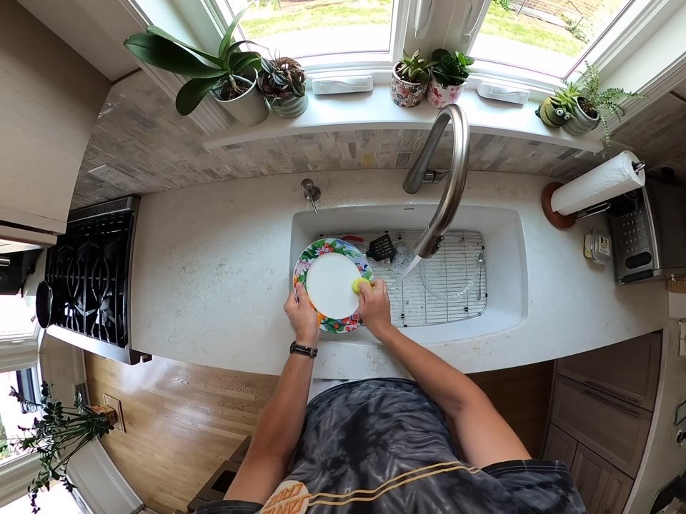 First-person view washing a plate in a kitchen sink